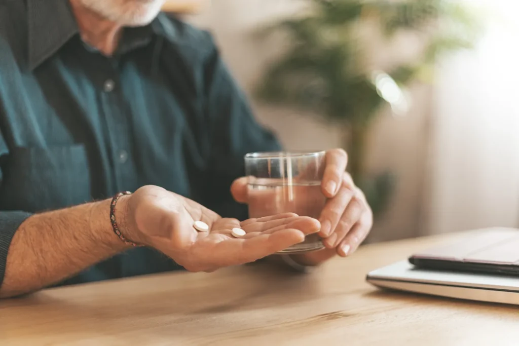 Senior man holding a handful of supplements.